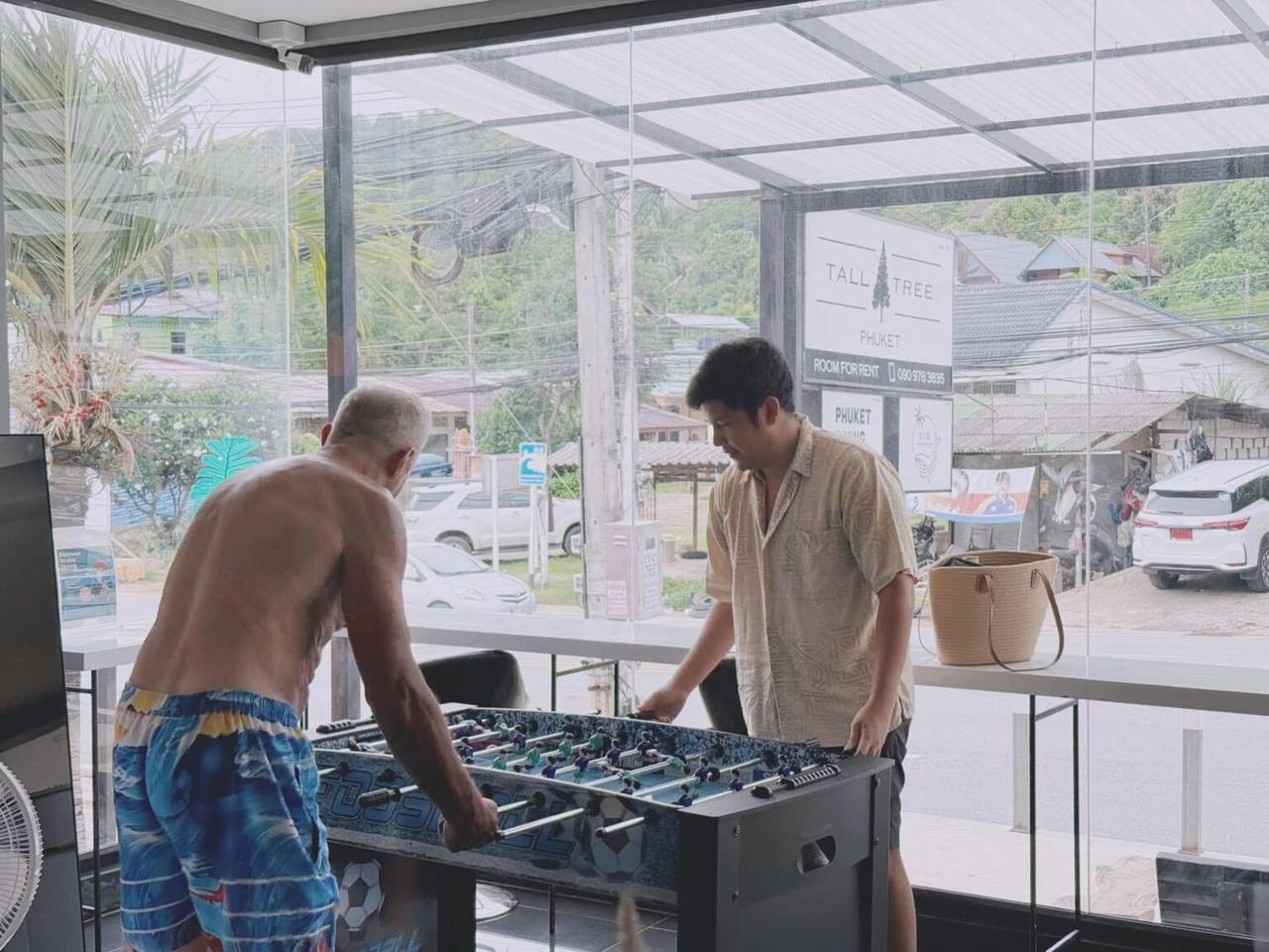 Guests playing table football in the bright common area at Tall Tree Kata