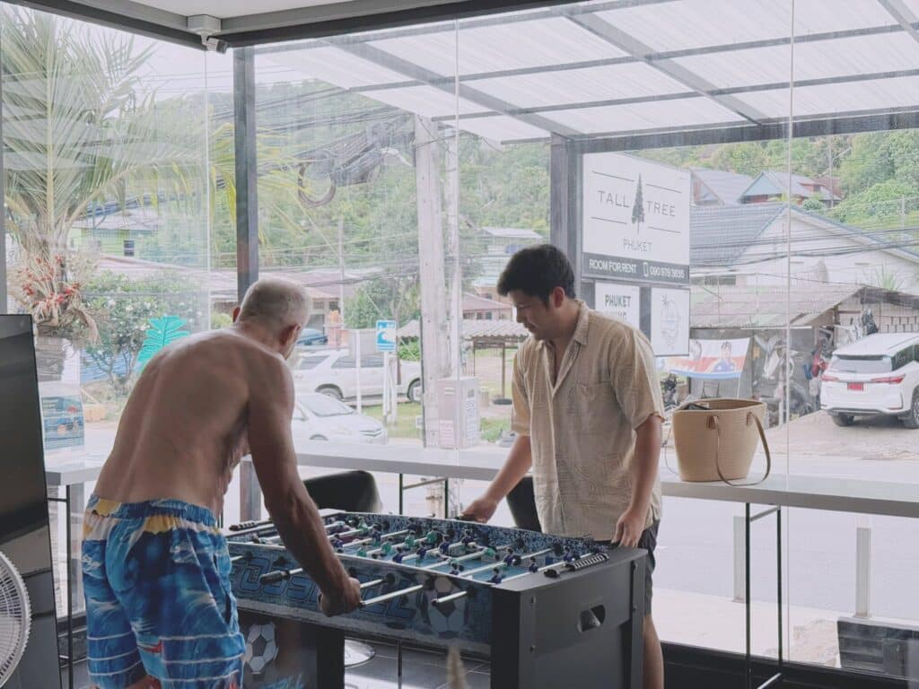 Guests enjoying a game of table football in the bright and airy common area of Tall Tree Kata.